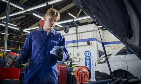 A Point S technician carrying out a car service, checking the engine oil and fluid levels