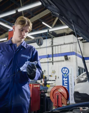 A Point S technician carrying out a car service, checking the engine oil and fluid levels